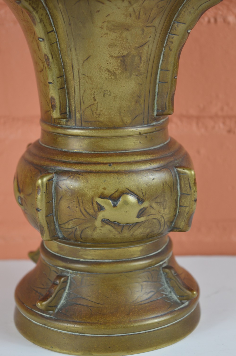 A cast bronze trumpet-shaped Chinese Gu vase with vertical flanges, a bulbous central section, and incised archaic pattern detailing. View III