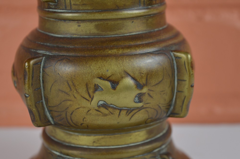 A cast bronze trumpet-shaped Chinese Gu vase with vertical flanges, a bulbous central section, and incised archaic pattern detailing. View V