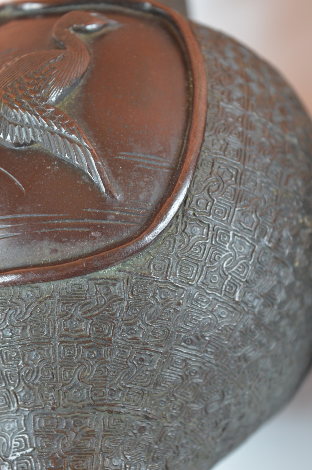 A pair of dark brown patinated Japanese bronze vases featuring dragon-form handles and relief panels depicting birds amongst aquatic foliage. View IV