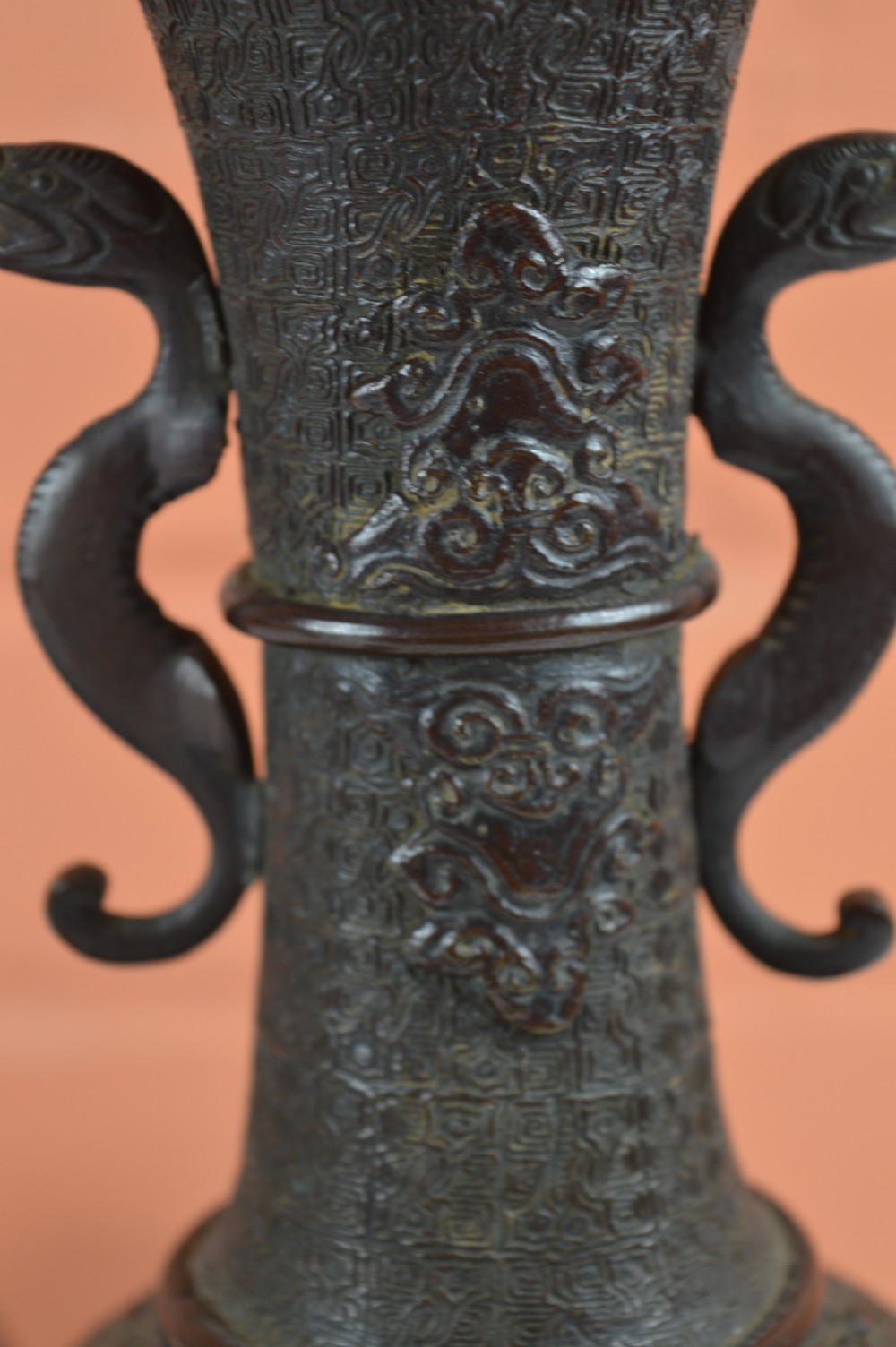 A pair of dark brown patinated Japanese bronze vases featuring dragon-form handles and relief panels depicting birds amongst aquatic foliage. View V
