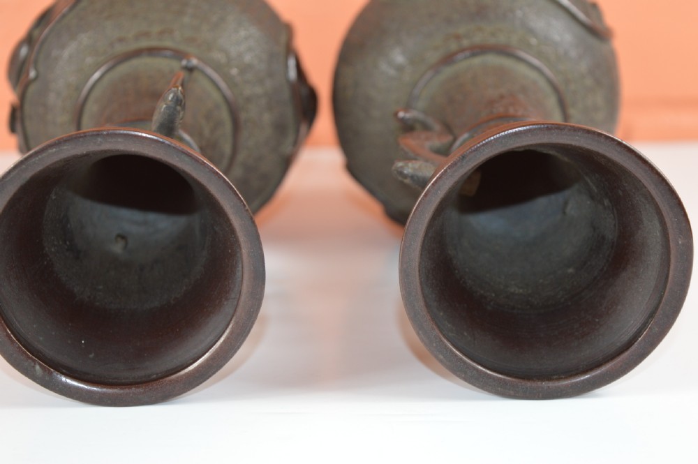 A pair of dark brown patinated Japanese bronze vases featuring dragon-form handles and relief panels depicting birds amongst aquatic foliage. View VI