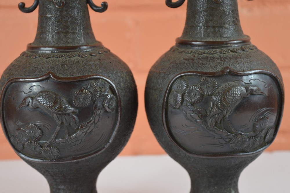 A pair of dark brown patinated Japanese bronze vases featuring dragon-form handles and relief panels depicting birds amongst aquatic foliage. View VII