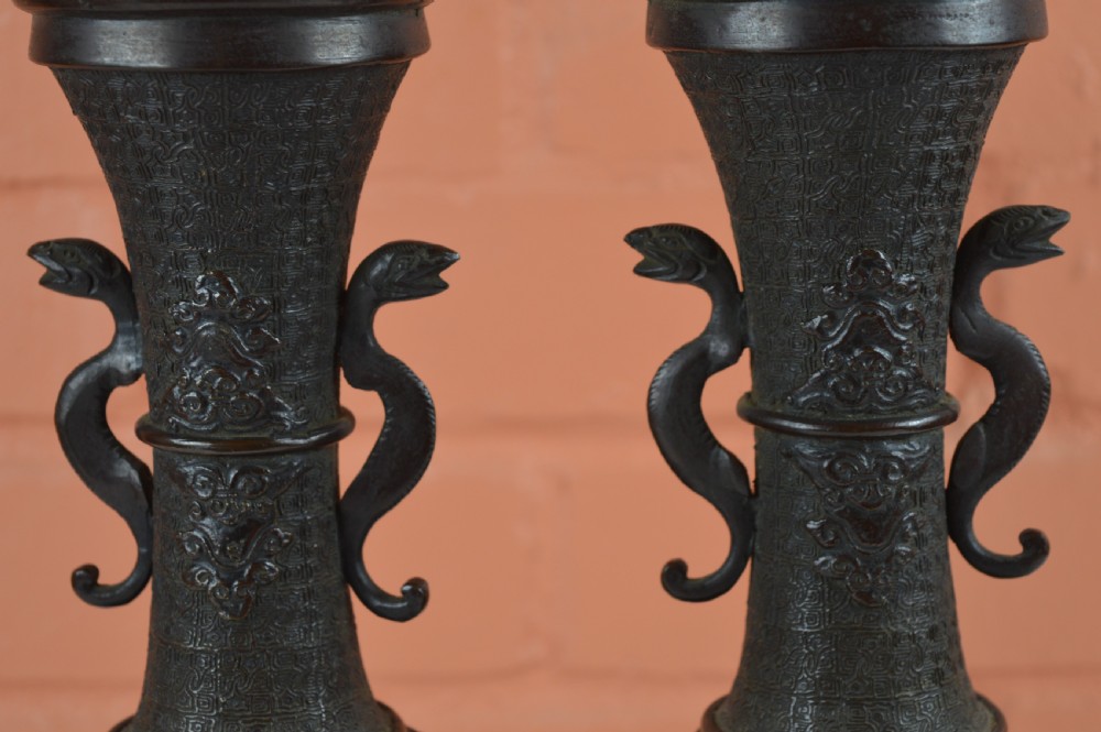 A pair of dark brown patinated Japanese bronze vases featuring dragon-form handles and relief panels depicting birds amongst aquatic foliage. View X