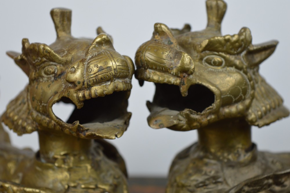 A pair of antique cast gilt bronze Tibetan temple lions featuring open mouths, chased body detail, and raised tails. View III