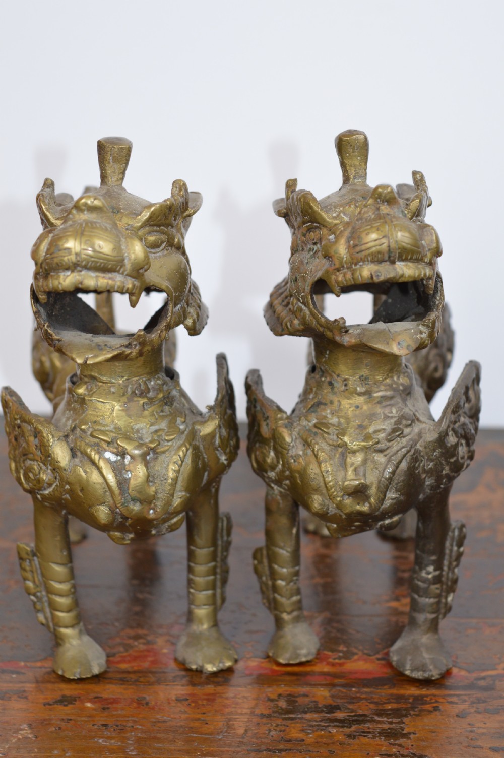A pair of antique cast gilt bronze Tibetan temple lions featuring open mouths, chased body detail, and raised tails. View V