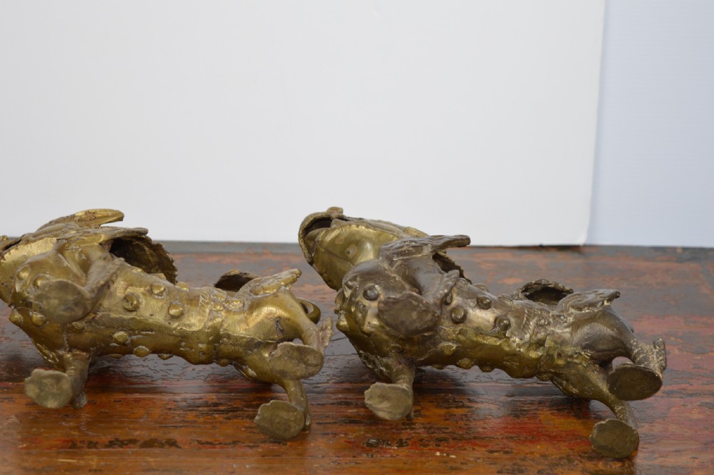 A pair of antique cast gilt bronze Tibetan temple lions featuring open mouths, chased body detail, and raised tails. View VII