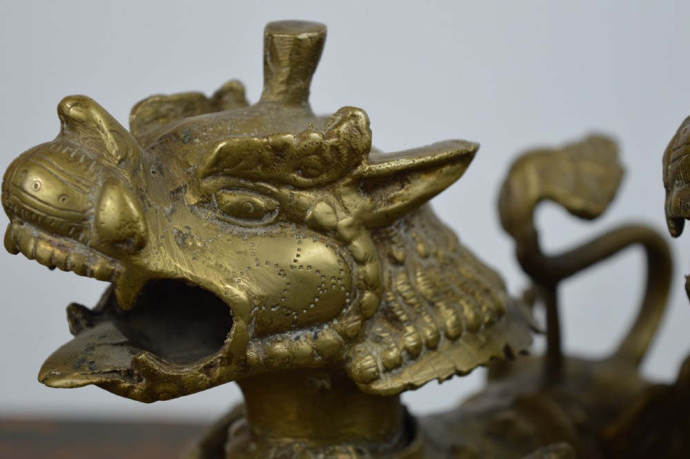 A pair of antique cast gilt bronze Tibetan temple lions featuring open mouths, chased body detail, and raised tails. View VIII