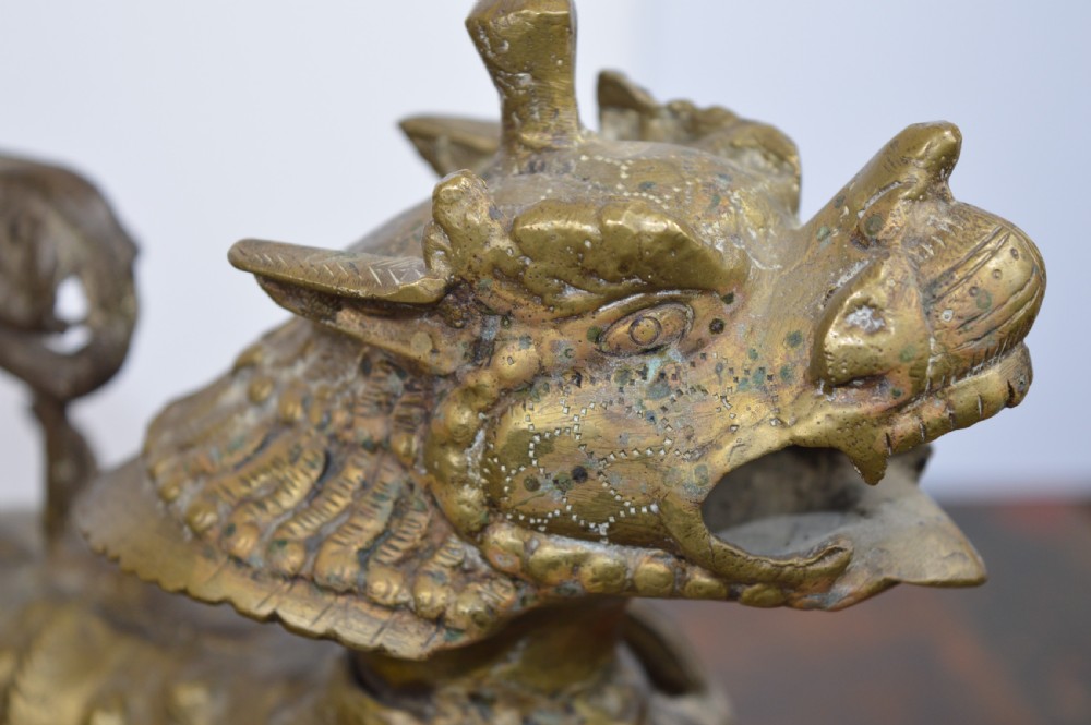 A pair of antique cast gilt bronze Tibetan temple lions featuring open mouths, chased body detail, and raised tails. View IX