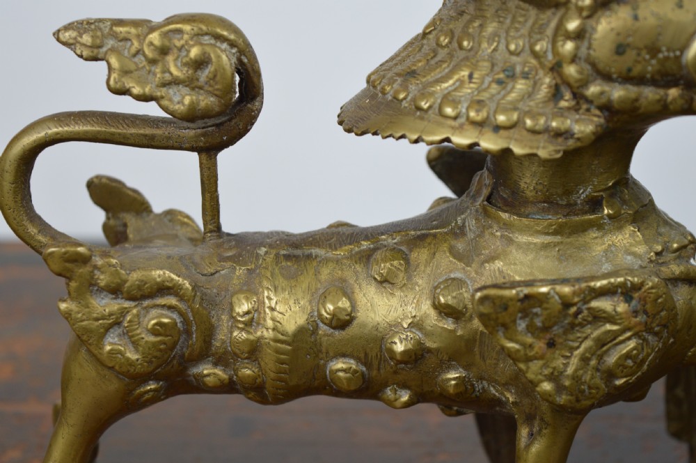 A pair of antique cast gilt bronze Tibetan temple lions featuring open mouths, chased body detail, and raised tails. View XI