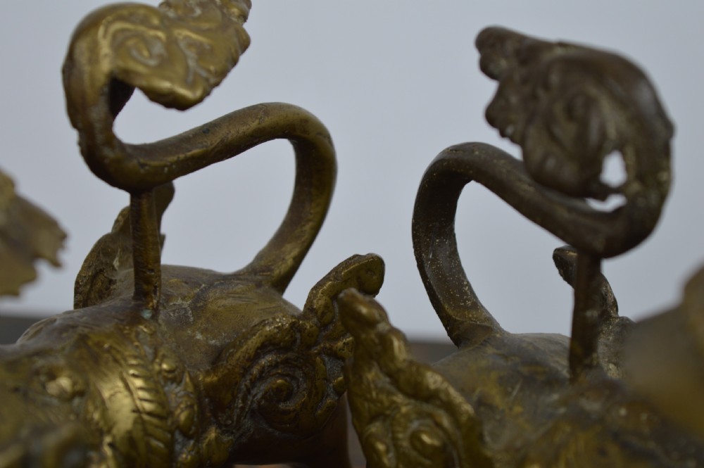 A pair of antique cast gilt bronze Tibetan temple lions featuring open mouths, chased body detail, and raised tails. View XII