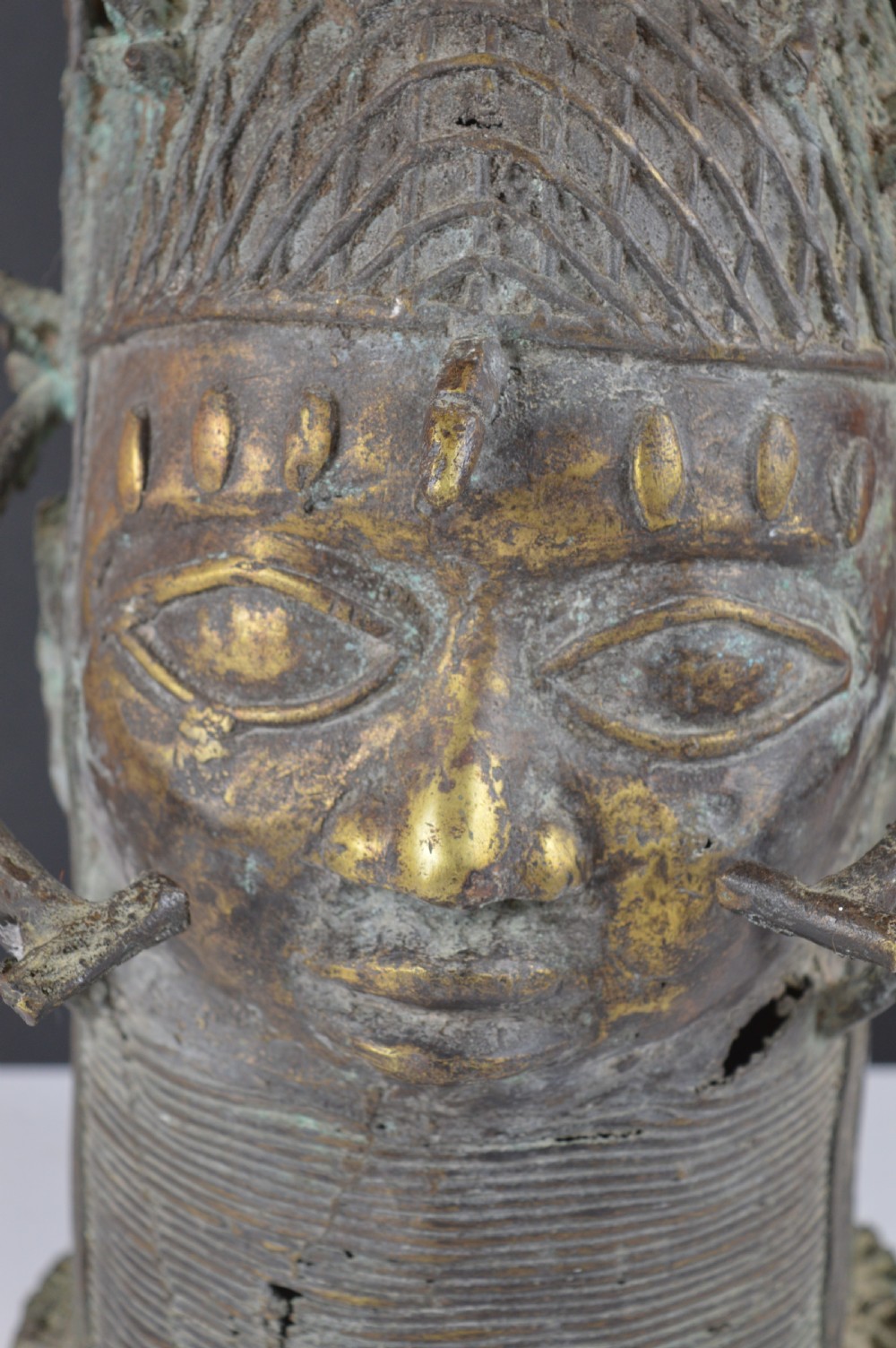 A cast bronze African bust featuring stylized facial features, a high ringed neck collar, and raised decorative elements on the headdress. View II
