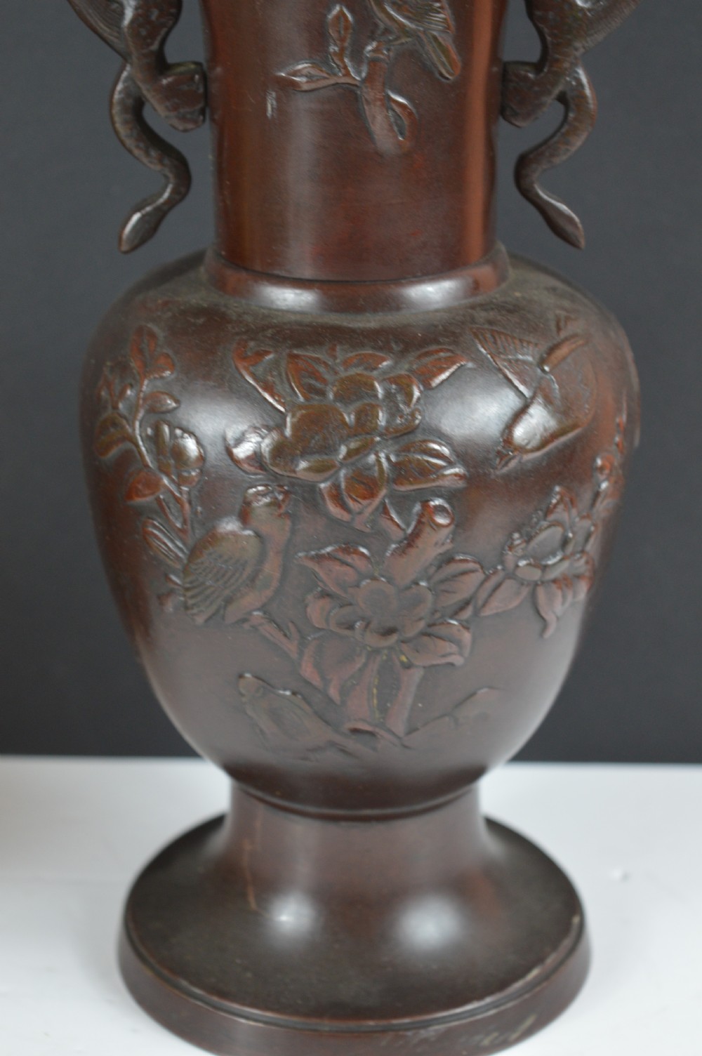 A cast dark bronze baluster vase featuring dragon-form side handles, a flared rim, and relief carvings of birds perched on flowering branches. View III