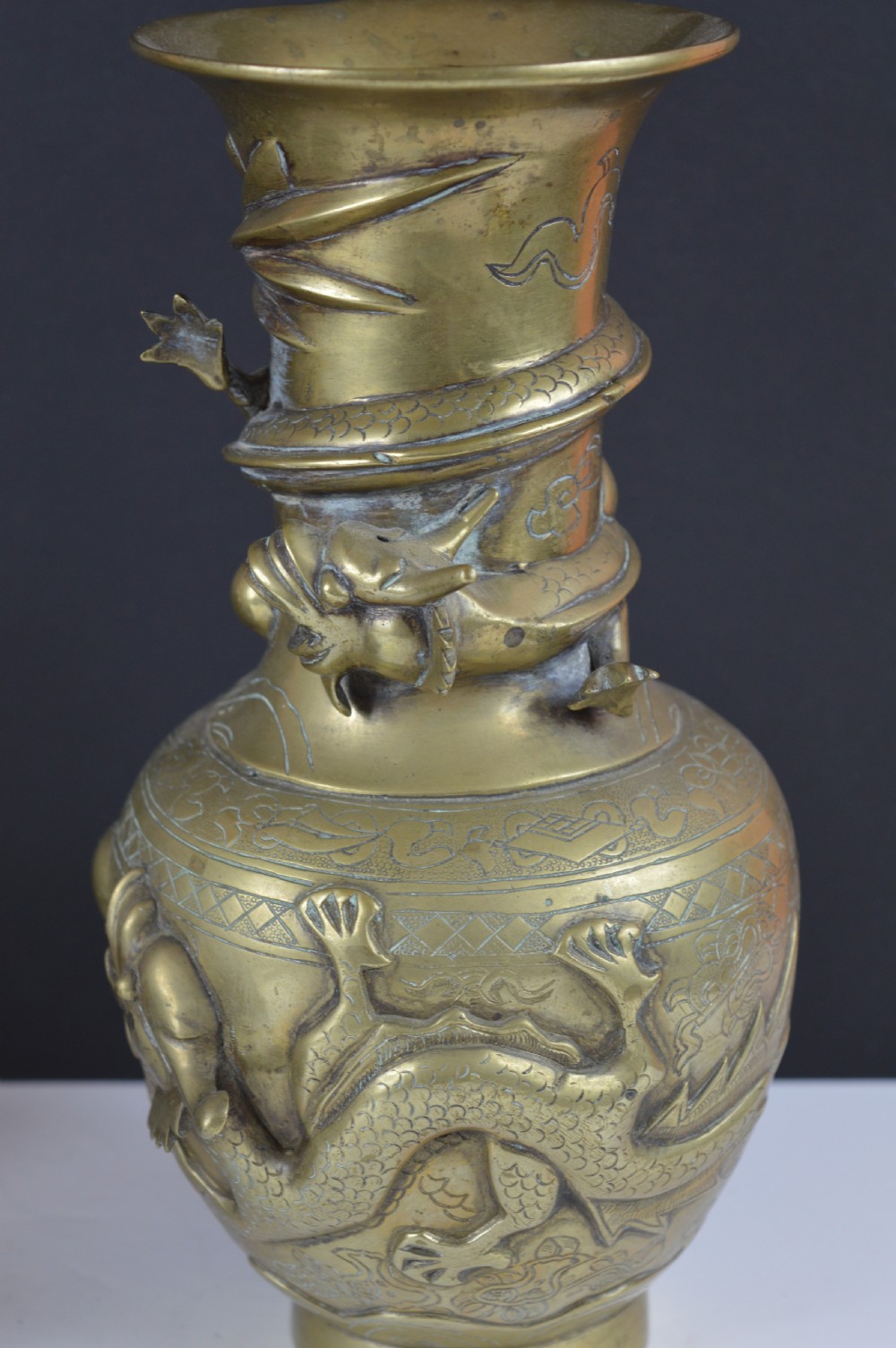 An antique brass baluster vase decorated with high-relief coiled dragons around the neck and body alongside engraved cloud patterns. View VI