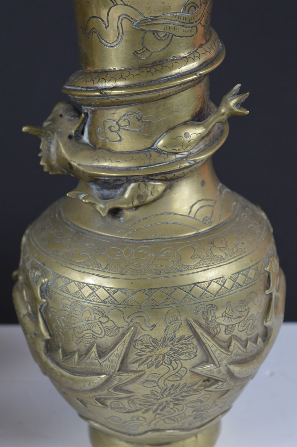 An antique brass baluster vase decorated with high-relief coiled dragons around the neck and body alongside engraved cloud patterns. View VII