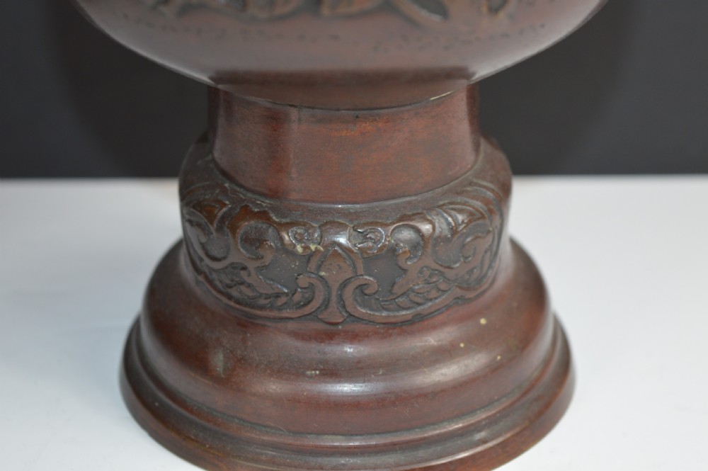 A dark brown patinated bronze vase with relief carvings of birds and flora, featuring flared rims and two stylized handles. View III