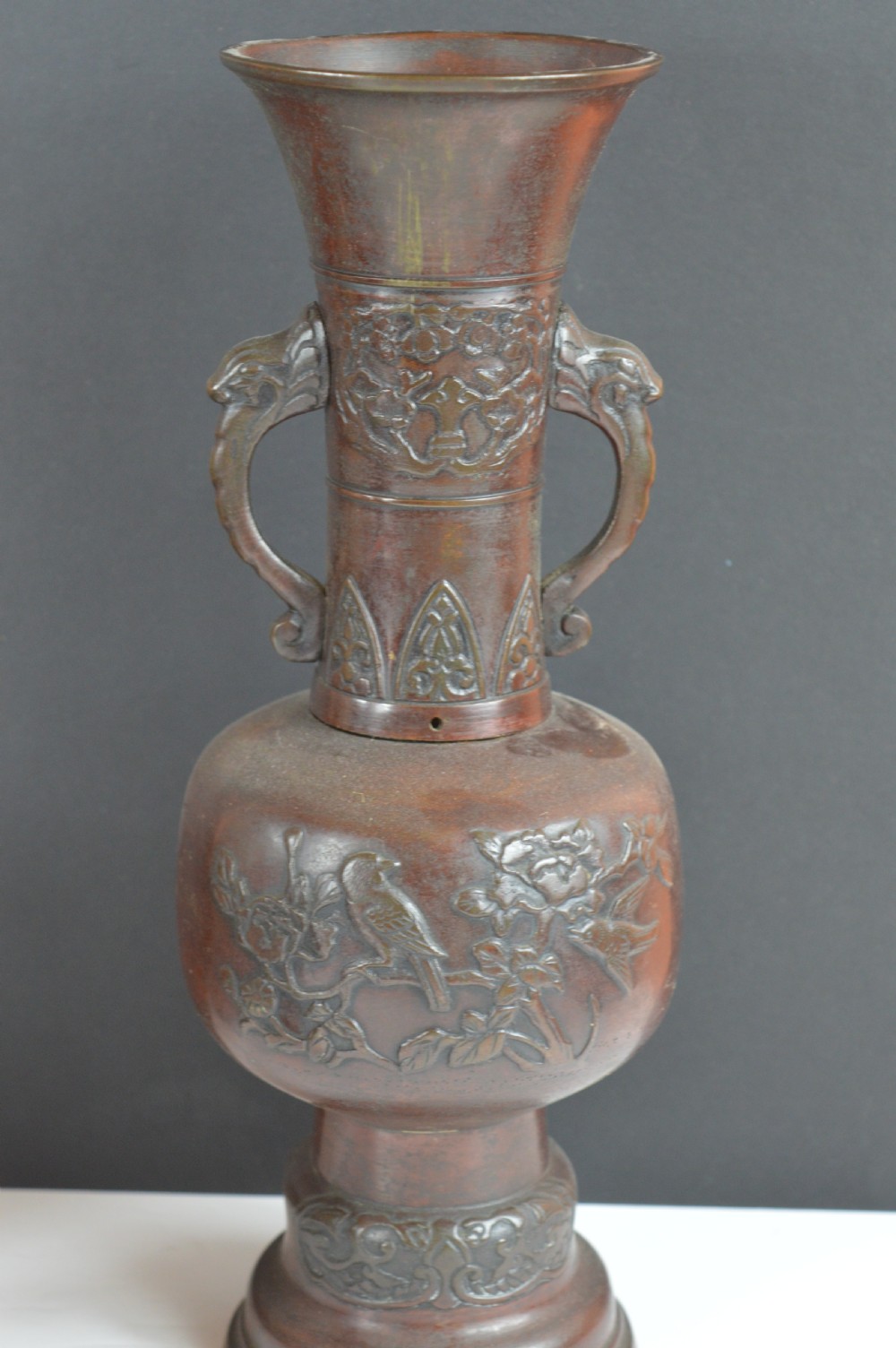 A dark brown patinated bronze vase with relief carvings of birds and flora, featuring flared rims and two stylized handles. View V