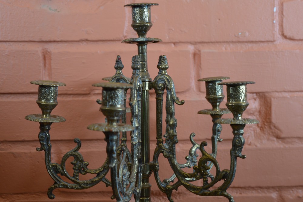 An ornate nineteenth-century French brass six-light candelabrum featuring elaborate scrollwork arms, an urn-shaped central column, and a cast footed base. View V