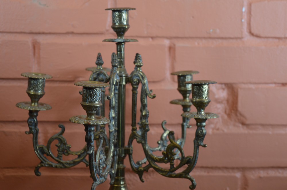 An ornate nineteenth-century French brass six-light candelabrum featuring elaborate scrollwork arms, an urn-shaped central column, and a cast footed base. View VI