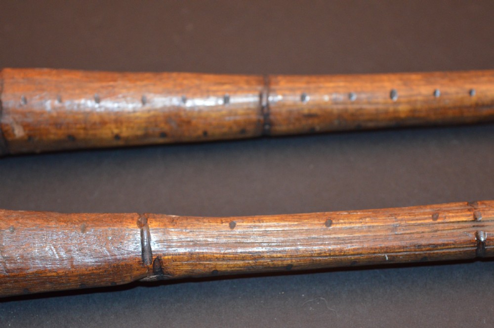 A pair of 19th-century carved Australian Aboriginal hardwood throwing clubs with pointed ends and incised dot decoration laid on a dark surface. View III