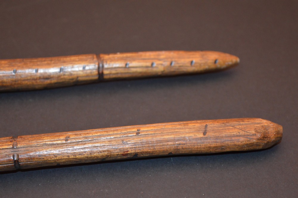 A pair of 19th-century carved Australian Aboriginal hardwood throwing clubs with pointed ends and incised dot decoration laid on a dark surface. View IV
