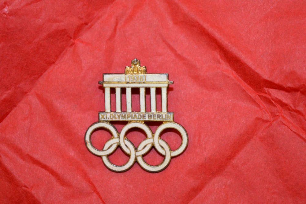 A 1936 Berlin Olympic Games enamel visitor badge featuring the Brandenburg Gate above five interconnected Olympic rings. View IV
