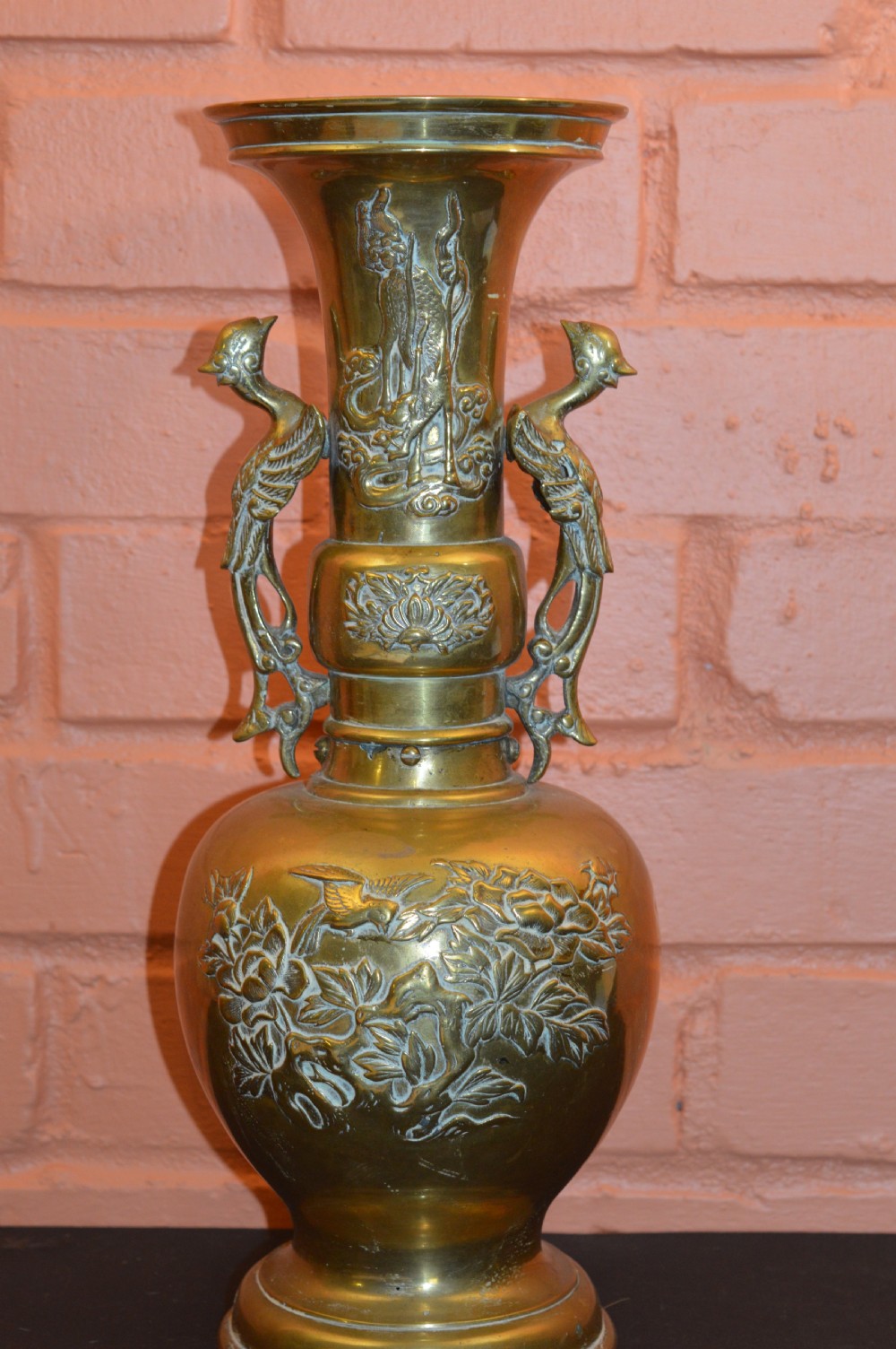 A nineteenth-century Chinese bronze vase featuring bird-shaped handles and intricate relief-carved floral motifs on a flared baluster body.