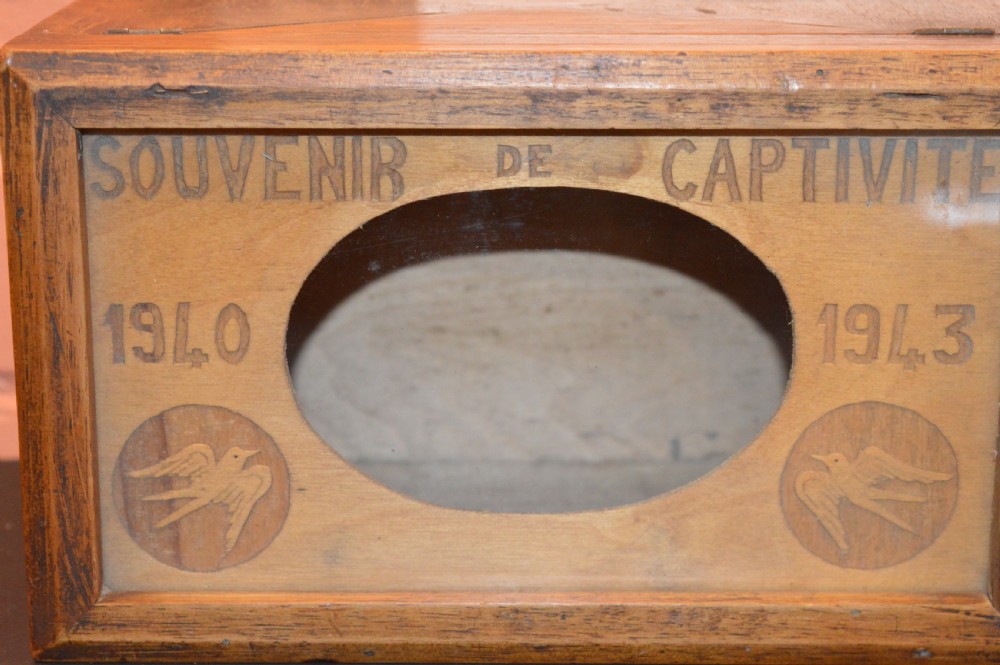 A four-piece collection of prisoner of war memorabilia including a carved wooden box, a wooden frame, a metal bell, and framed wartime documents. View III