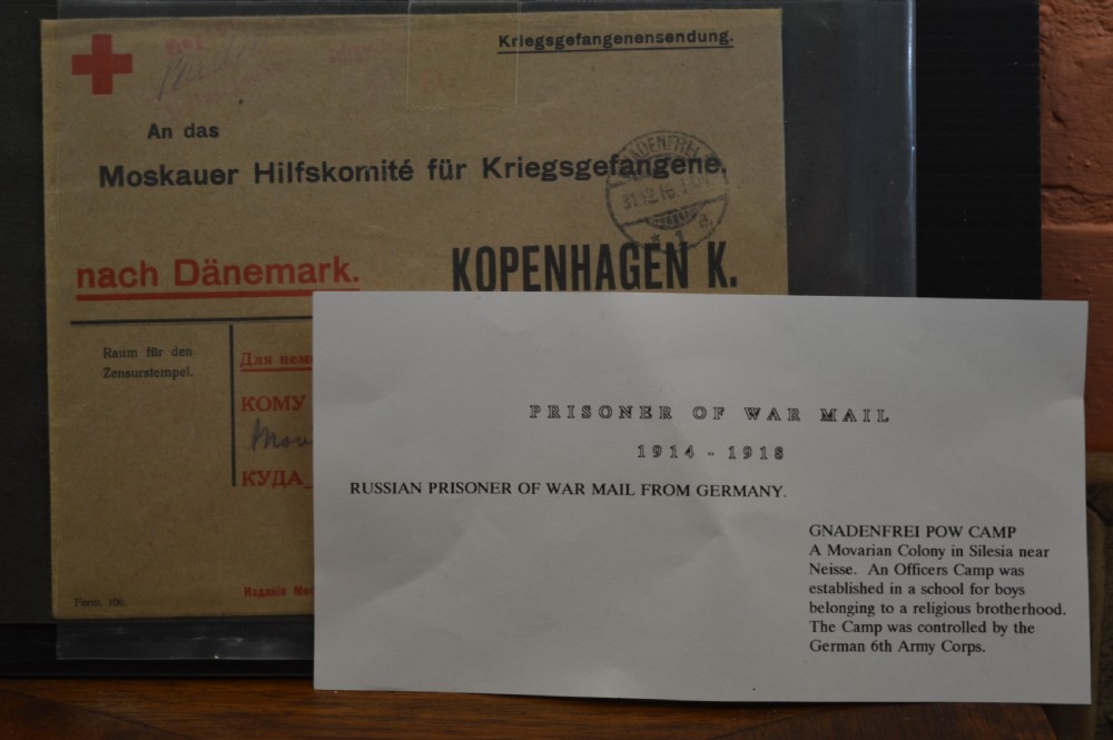 A four-piece collection of prisoner of war memorabilia including a carved wooden box, a wooden frame, a metal bell, and framed wartime documents. View IV