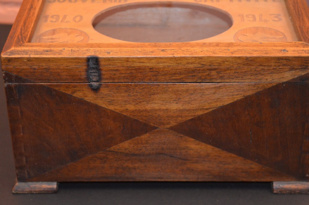 A four-piece collection of prisoner of war memorabilia including a carved wooden box, a wooden frame, a metal bell, and framed wartime documents. View VII