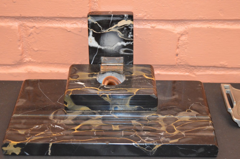 Two antique desk inkstands, one composed of black and gold veined marble with a built-in pen groove, and the second crafted from silver-toned metal with relief detailing. View II