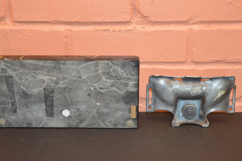 Two antique desk inkstands, one composed of black and gold veined marble with a built-in pen groove, and the second crafted from silver-toned metal with relief detailing. View V