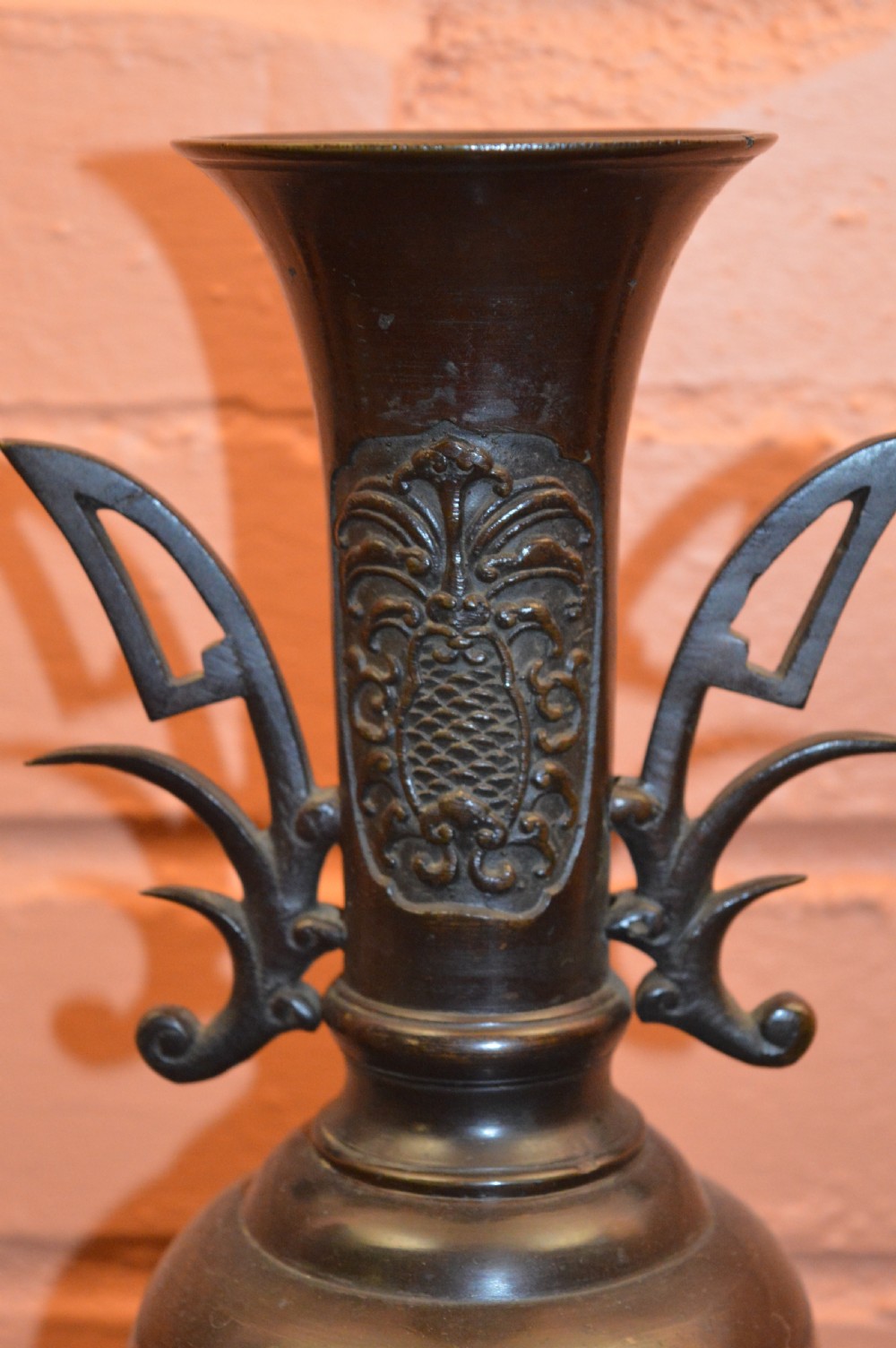 A dark brown patinated Japanese bronze vase featuring stylised handles, a flared neck, and raised relief carvings of birds over waves. View III