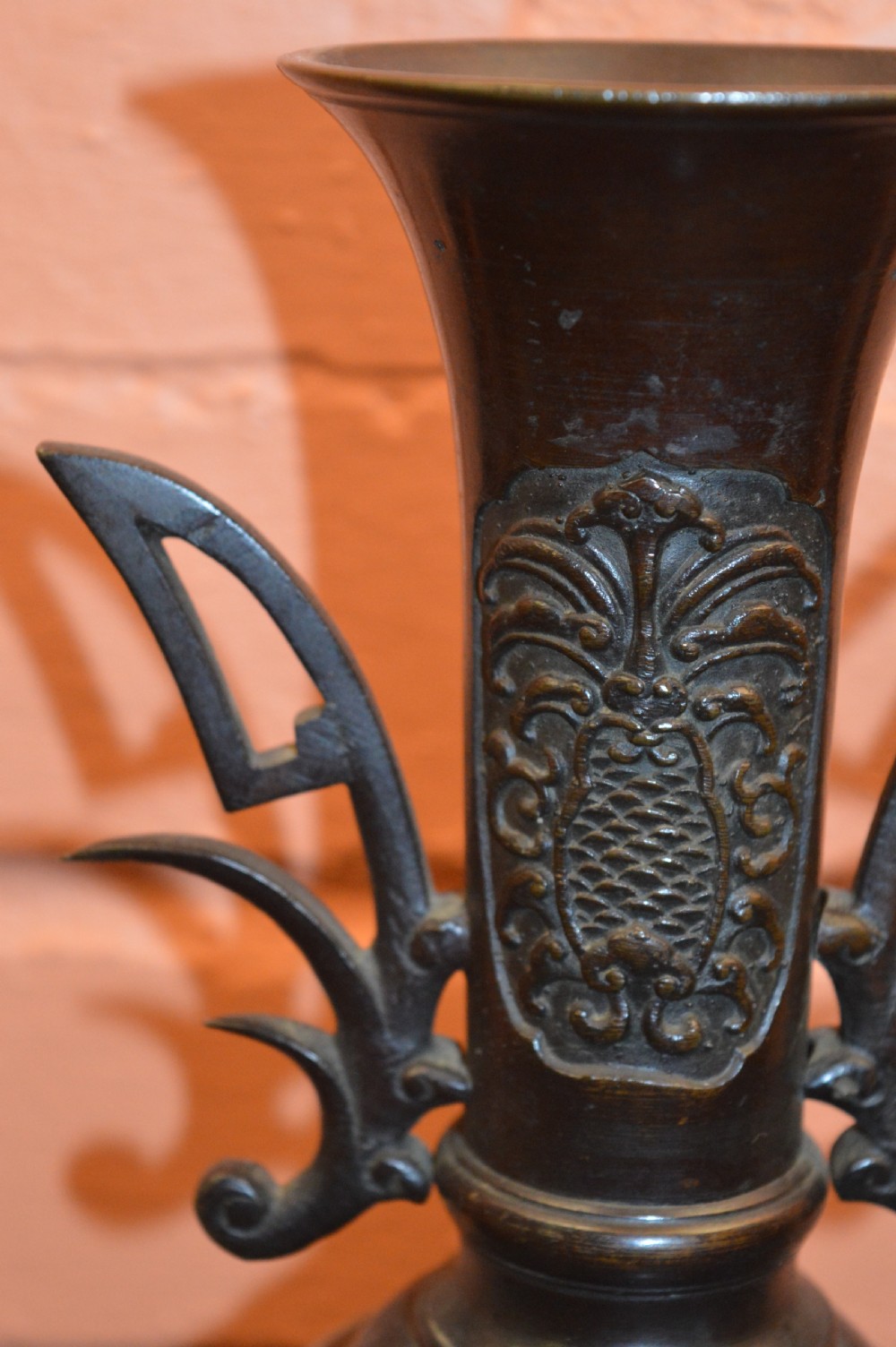A dark brown patinated Japanese bronze vase featuring stylised handles, a flared neck, and raised relief carvings of birds over waves. View VI