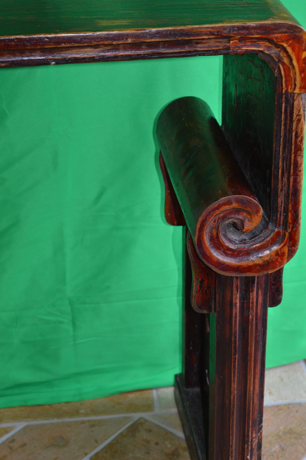 A long dark hardwood Tibetan altar table featuring a flat rectangular top supported by upright legs with prominent carved scroll terminals. View IV
