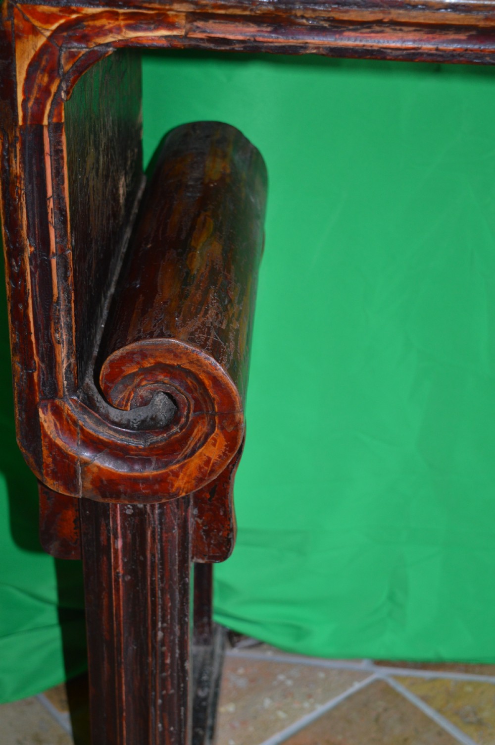 A long dark hardwood Tibetan altar table featuring a flat rectangular top supported by upright legs with prominent carved scroll terminals. View X