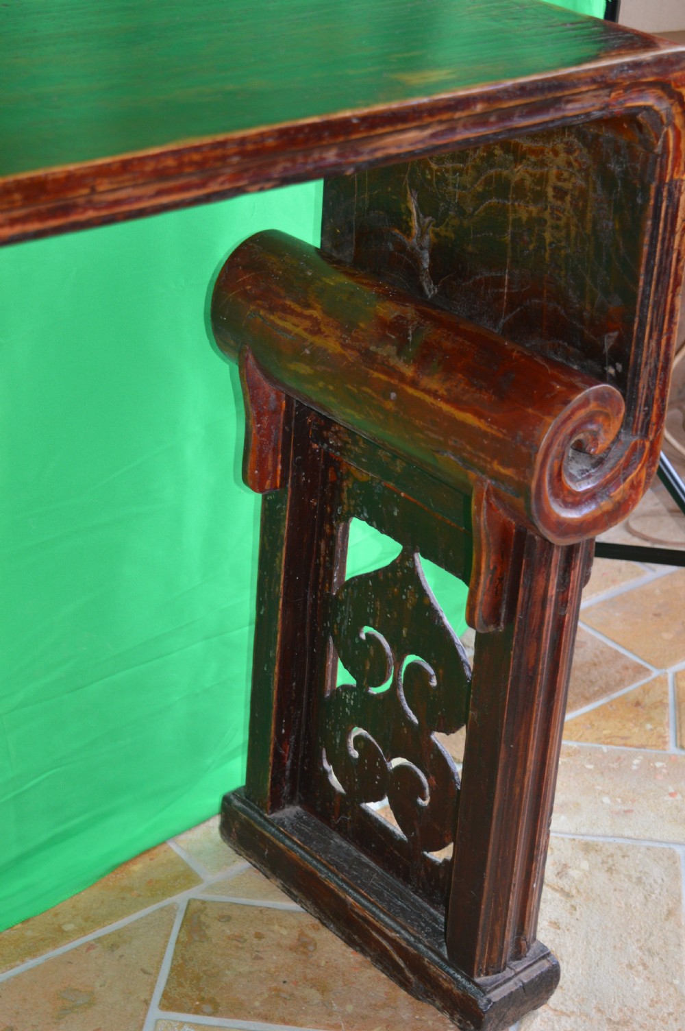 A long dark hardwood Tibetan altar table featuring a flat rectangular top supported by upright legs with prominent carved scroll terminals. View XI