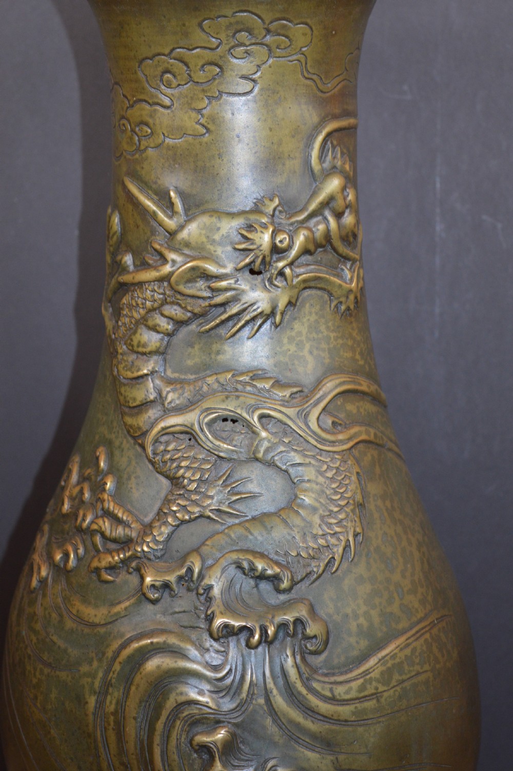 A tall baluster-shaped bronze vase featuring a high-relief carved dragon emerging from swirling waves and cloud motifs. View II