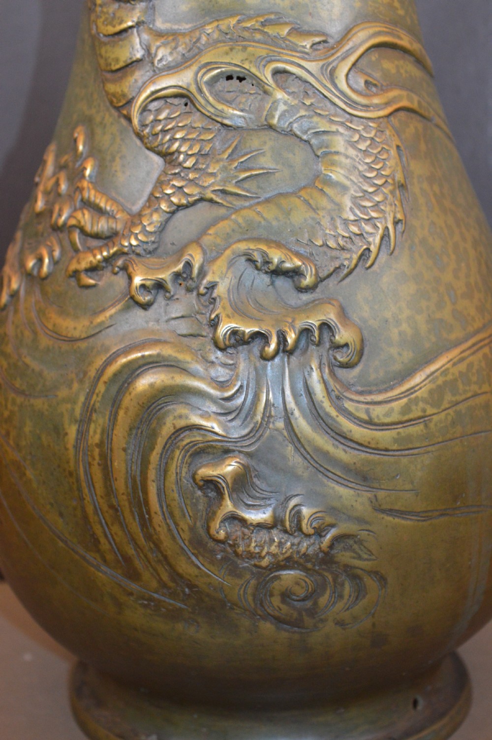 A tall baluster-shaped bronze vase featuring a high-relief carved dragon emerging from swirling waves and cloud motifs. View III