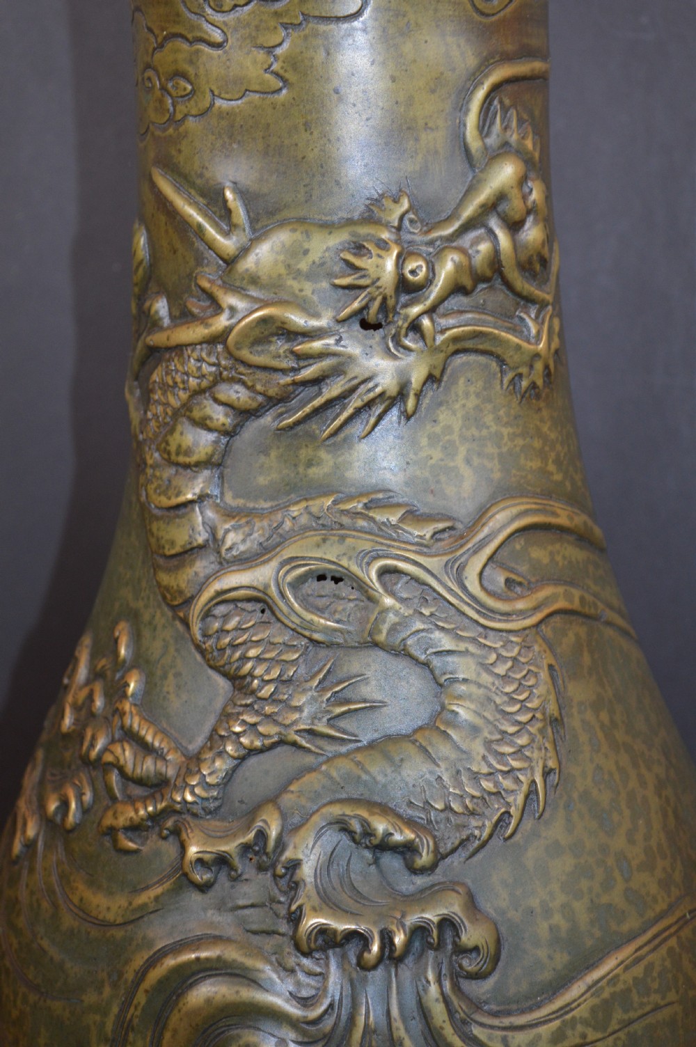 A tall baluster-shaped bronze vase featuring a high-relief carved dragon emerging from swirling waves and cloud motifs. View IV