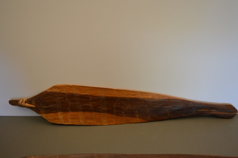 A pair of 19th-century carved Indigenous Australian wooden woomeras displaying elongated curved profiles and natural timber grain. View VI