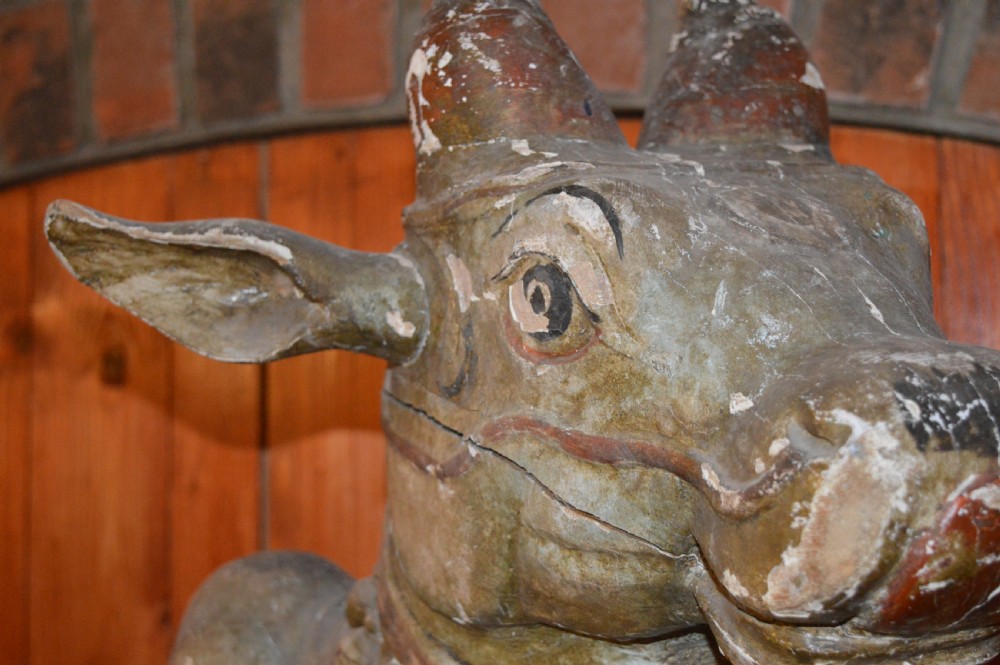A large antique carved wooden Nandi bull statue featuring worn polychrome paint and decorative carved bells around its neck. View IV