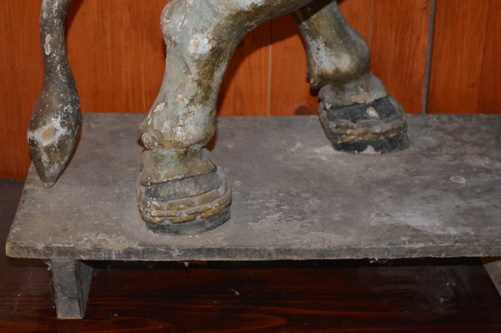 A large antique carved wooden Nandi bull statue featuring worn polychrome paint and decorative carved bells around its neck. View X