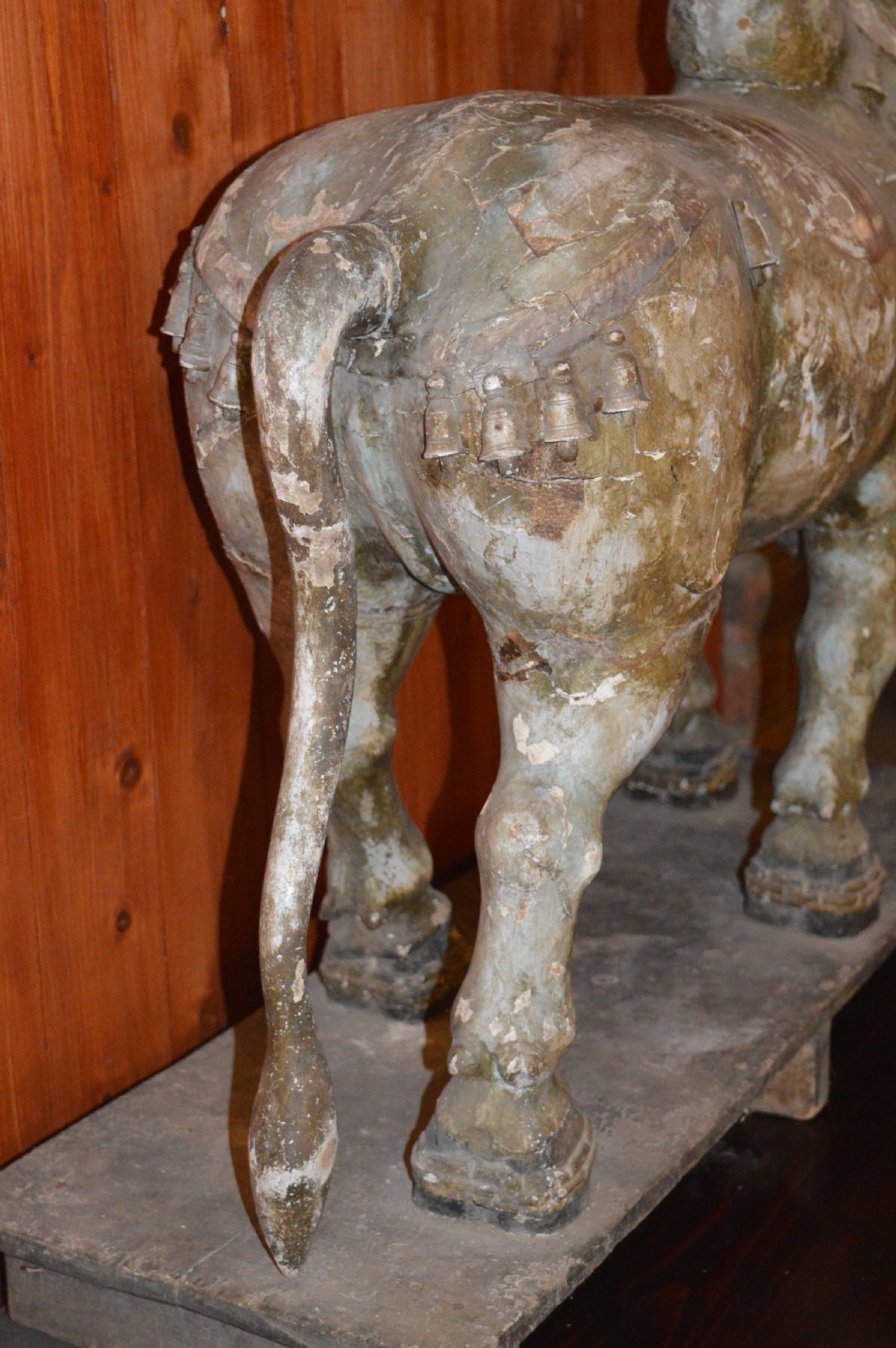 A large antique carved wooden Nandi bull statue featuring worn polychrome paint and decorative carved bells around its neck. View XIV