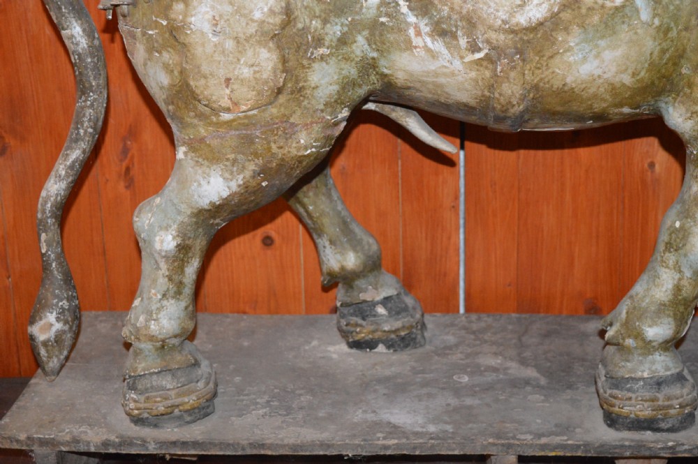 A large antique carved wooden Nandi bull statue featuring worn polychrome paint and decorative carved bells around its neck. View XV