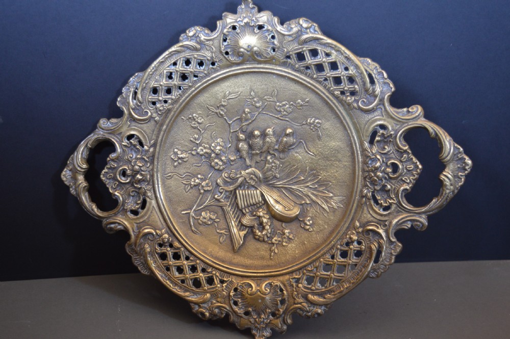 A cast bronze decorative centrepiece plate featuring a high-relief central scene with birds and musical instruments surrounded by an openwork lattice border and scroll handles. View II