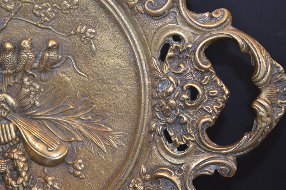 A cast bronze decorative centrepiece plate featuring a high-relief central scene with birds and musical instruments surrounded by an openwork lattice border and scroll handles. View IV