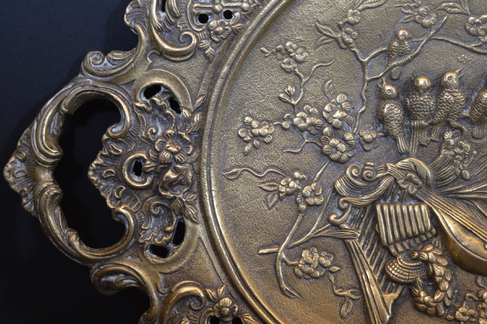 A cast bronze decorative centrepiece plate featuring a high-relief central scene with birds and musical instruments surrounded by an openwork lattice border and scroll handles. View V