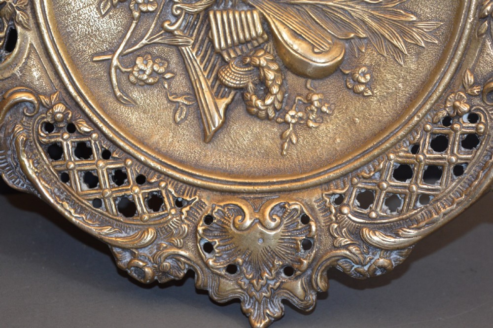 A cast bronze decorative centrepiece plate featuring a high-relief central scene with birds and musical instruments surrounded by an openwork lattice border and scroll handles. View VI