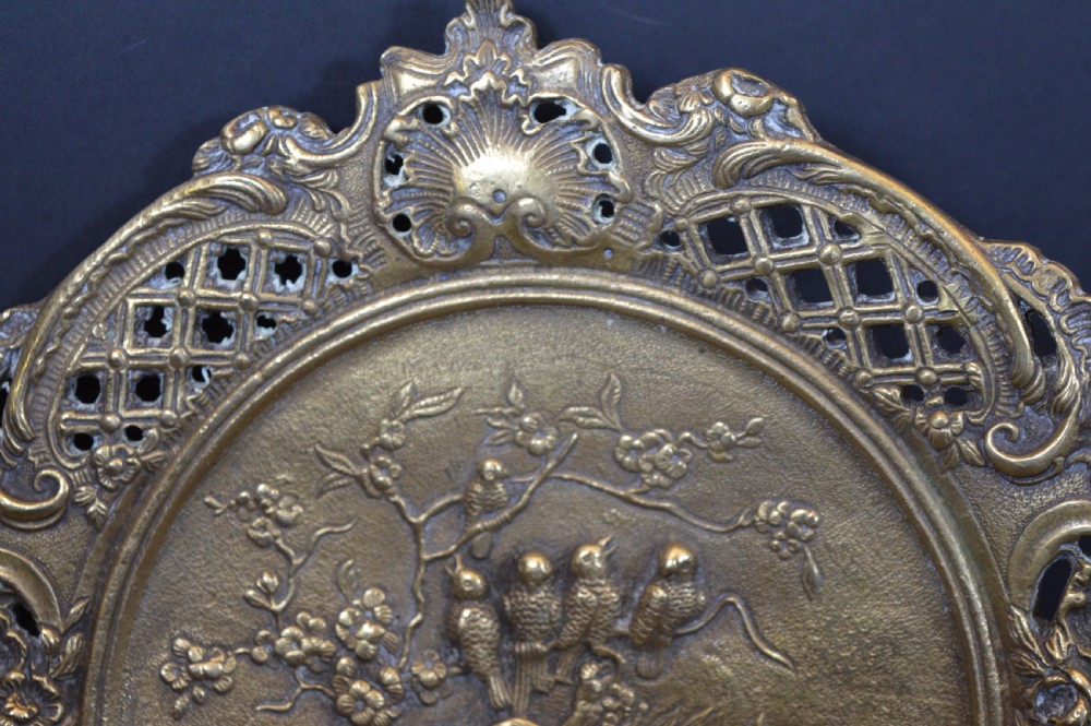 A cast bronze decorative centrepiece plate featuring a high-relief central scene with birds and musical instruments surrounded by an openwork lattice border and scroll handles. View VII
