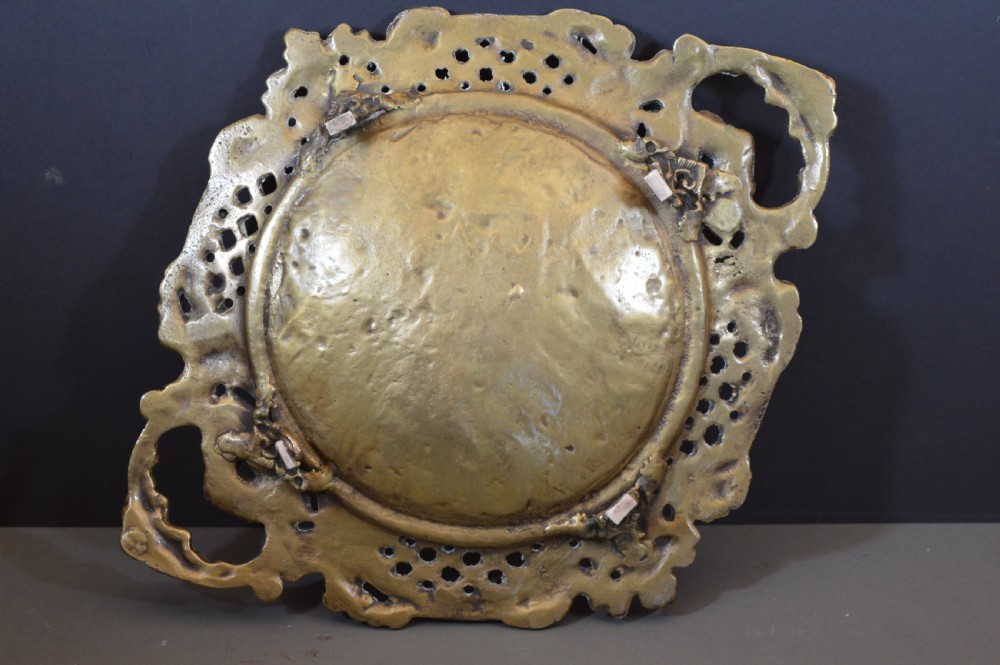 A cast bronze decorative centrepiece plate featuring a high-relief central scene with birds and musical instruments surrounded by an openwork lattice border and scroll handles. View X